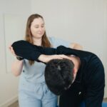 A physiotherapist assisting a patient with a stretching exercise for chronic back pain treatment.