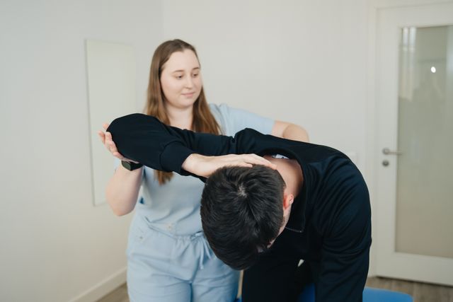 A physiotherapist assisting a patient with a stretching exercise for chronic back pain treatment.