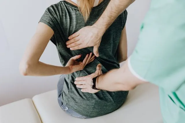 A healthcare professional examining a patient experiencing back pain, illustrating discomfort associated with potential ligament injuries.