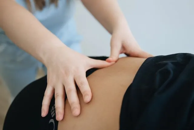 A physiotherapist performing manual therapy on a patient's lower back to help relieve back pain.